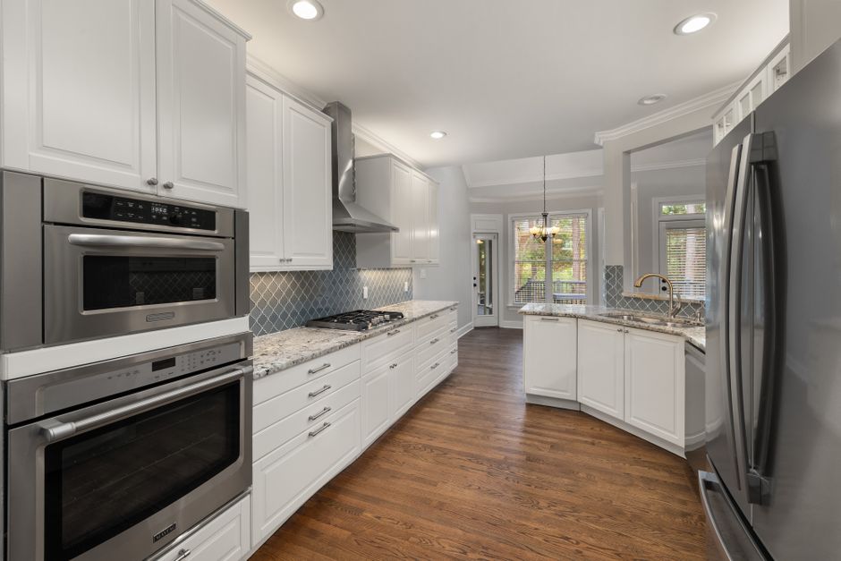 Spacious modern kitchen with white cabinetry and stainless steel appliances.
